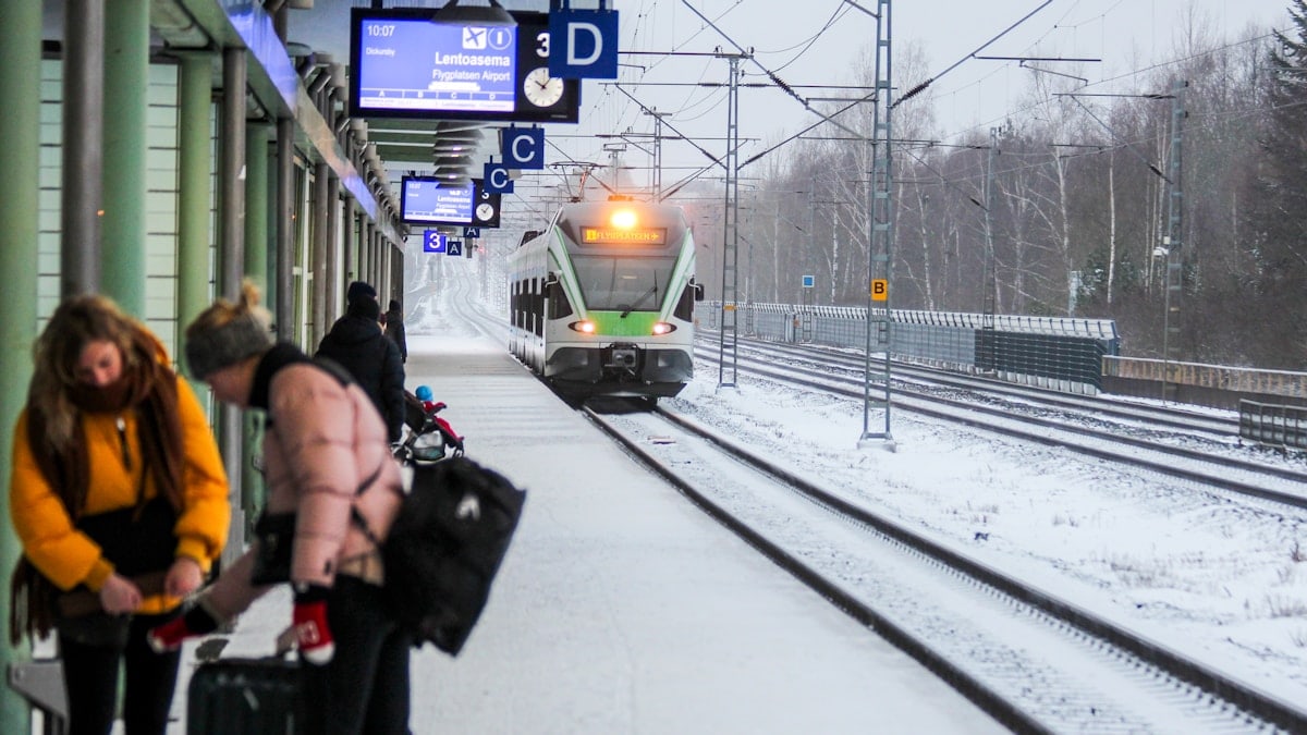 two women holding luggage standing near railway